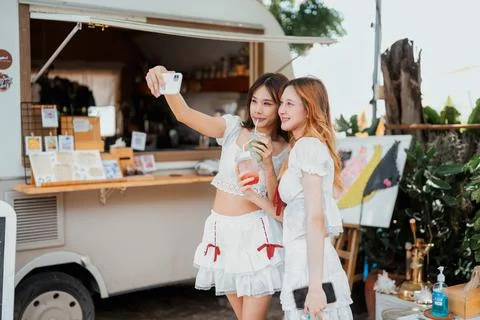 Friends enjoying refreshing drinks while taking selfies at a vibrant outdoo.. Stock Photos