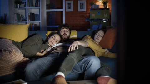 Friends falling asleep on the sofa in front of the TV Stock Footage 128778934
