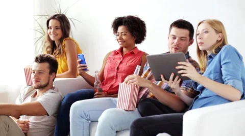 Friends with gadgets and beer watching tv at home Stock Footage
