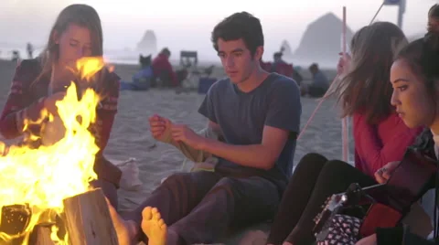 Friends hang out by fire Stock Footage 53257352