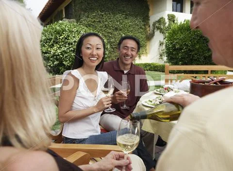 Friends Having Dinner And Drinks In Garden Stock-Fotos