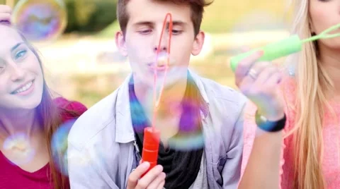 Friends having fun and blowing soap bubbles in park. Stock Footage 53484294