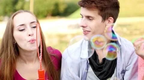 Friends having fun and blowing soap bubbles in park Stock Footage 53605912