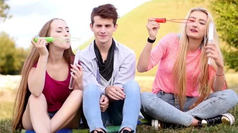 Friends having fun and blowing soap bubbles in park Stock Footage 53606049