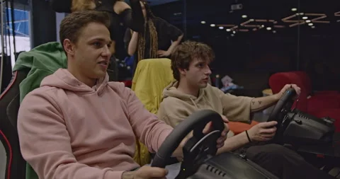 Friends Having Fun Playing Racing Games at an Entertainment Center Stock Footage 312068151
