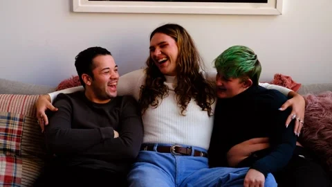 Friends having laughing, sitting on sofa. Millennial trans enjoying friendship. Stock Footage 242774334