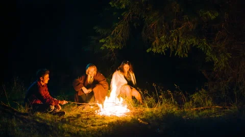 Friends having a rest in forest camp at night near bonfire 库存影片 64907608