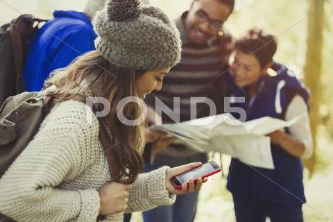 Friends hiking checking map and GPS on smart phone Stock Photos
