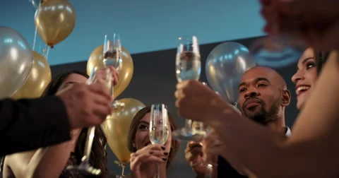 Friends holding up champagne flutes together in a toast at party Stock Footage
