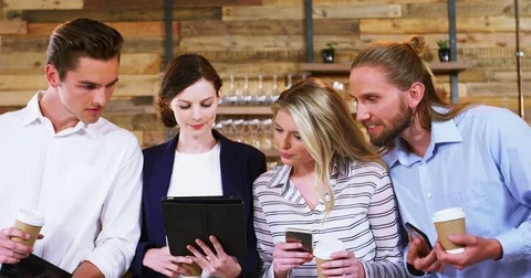 Friends holding disposable coffee cup and using digital tablet and mobile phone Stock Footage