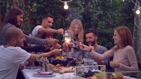 Friends holding lit sparklers at a dinner party Stock Footage