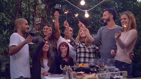 Friends holding lit sparklers at a dinner party Stock Footage