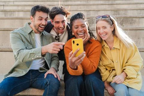 Friends joyfully sharing laughter while watching a funny video on a smartphone Stock Photos
