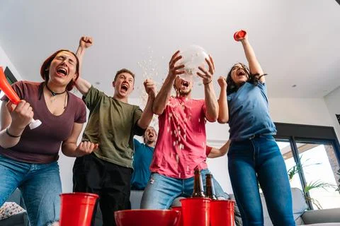 Friends jumping for joy, throwing popcorn in the air after their team's victory Stock Photos