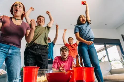 Friends jumping for joy watching e-sports on TV after their team's victory Stock Photos