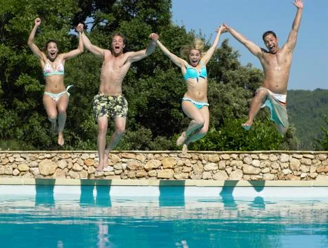 Friends jumping into pool Stock Photos