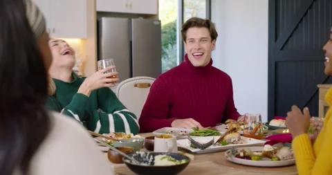 Friends at kitchen table seeing blond raising glass causing man in red top Stock Footage 344460622