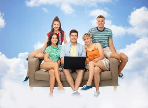 Friends with laptop computer on sofa over clouds Stock Photos