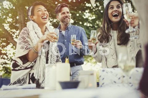 Friends laughing and drinking champagne at birthday party Stock Photos