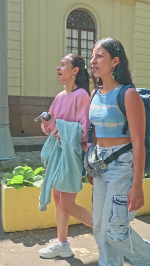 Friends Laughing and Pointing While Walking Together on a Sunny City Street. 動画素材 332944992
