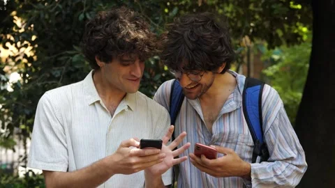 Friends Laughing Together at the Park While Watching a Video on Their Smartphone Stock Footage 285538429
