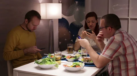 Friends looking on smartphone during dinner Stock Footage 58101293