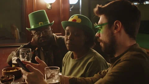 Friends Ordering Taxi While Hanging out at Bar Counter on St Patricks Day Stock Footage 290452751