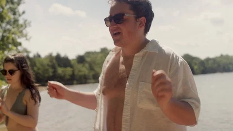Friends partying and dancing on a beach next to a forest lake Stock-Footage 116776972