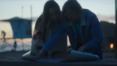 Friends plan out route in a map, chill evening at west coast Видео 127409682