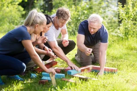 Friends Planning While Stacking Building Blocks On Grassy Field Stock Photos