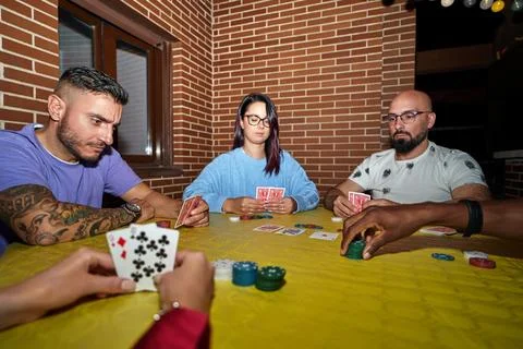 Friends playing cards game while sitting on a table outdoors in a terrace. Foto stock