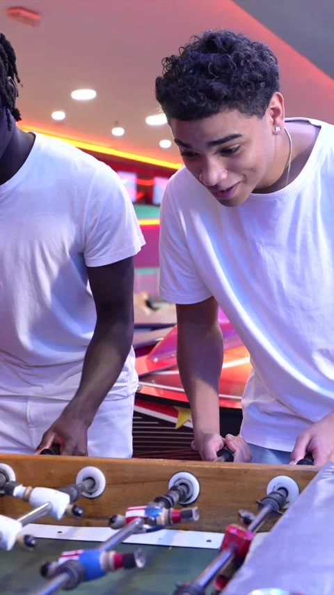 Friends playing foosball table game in arcade Stock Footage 308262289