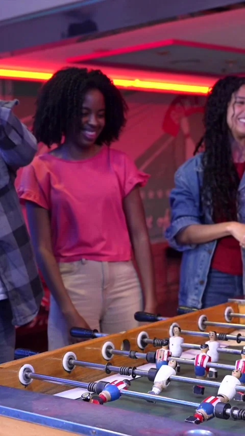 Friends playing foosball table soccer in an arcade Stock Footage 308262299