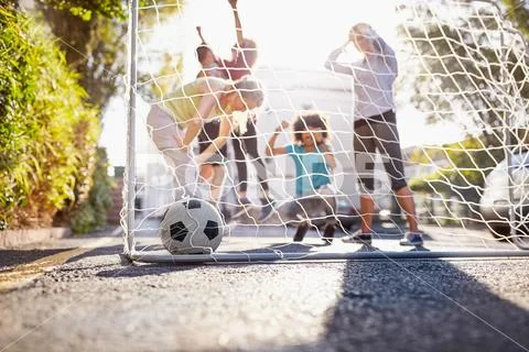 Friends playing soccer on sunny urban summer street Stock Photos