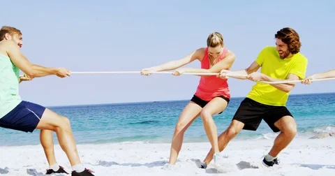 Friends playing tug of war on the beach Stock Footage 78699445