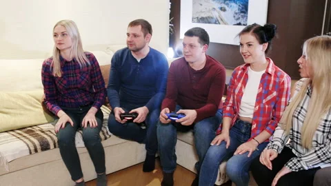 Friends playing video games while laughing in the living room Stock Footage 96063629