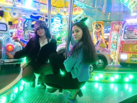 Friends posing while crouching on the platform of a fair attraction at night Stock Photos