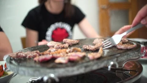 Friends preparing their own meat at hot stone. Video stock 241412866
