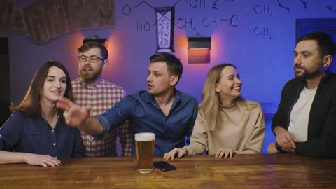 Friends in pub at bar counter try to order food and drink. People have fun glad Stock Footage 154266725