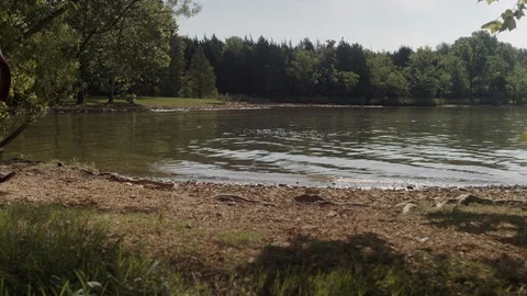 Friends put down a blanket on a rocky beach next to a lake on a summer day Stock Footage 116758031