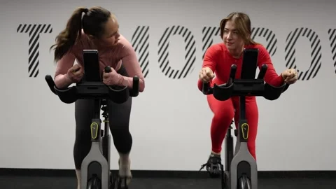 Friends race on exercise bikes Stock Footage 337114936