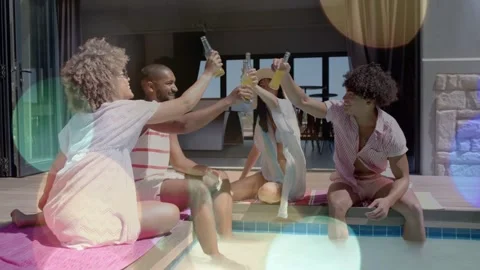 Friends raising bottles at pool edge initiating toast, sipping while lens flare Stock Footage 332981817