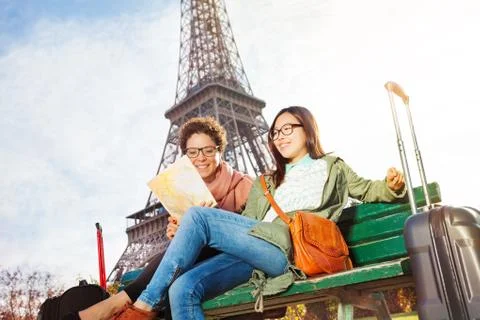 Friends reading map of Paris sitting on the bench Foto stock