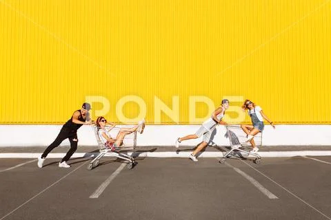Friends ride on carts, near the supermarket, a great pastime, a group of youn Stock Photos