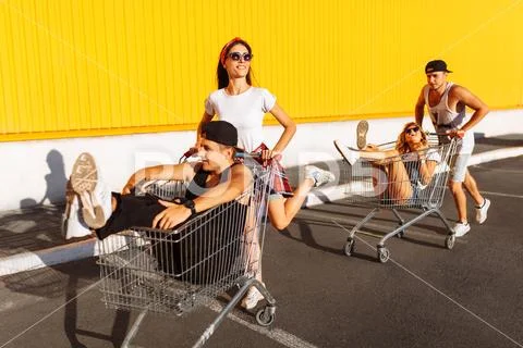 Friends ride on carts, near the supermarket, a great pastime, a group of youn Stock Photos