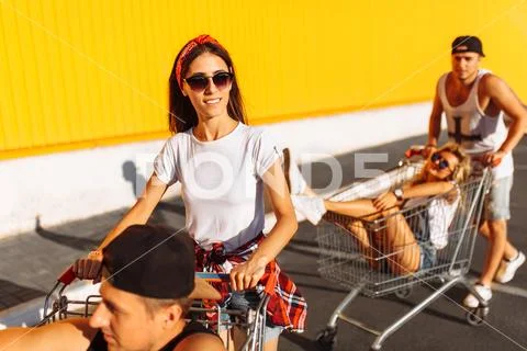 Friends ride on carts, near the supermarket, a great pastime, a group of youn Stock Photos