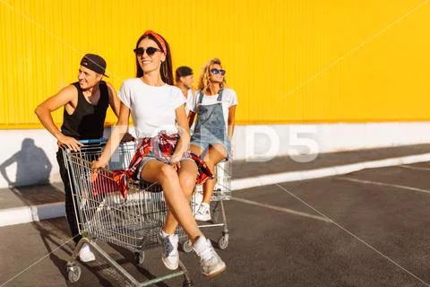Friends ride on carts, near the supermarket, a great pastime, a group of youn Stock Photos