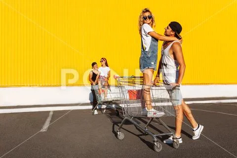 Friends ride on carts, near the supermarket, a great pastime, a group of youn Stock Photos