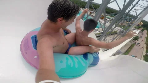 Friends rides from the slide on the inflatable circle in the water park 库存影片 102088757