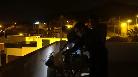 Friends on the rooftop preparing for a grill at night with lantern at a beach Stock Footage 155790525